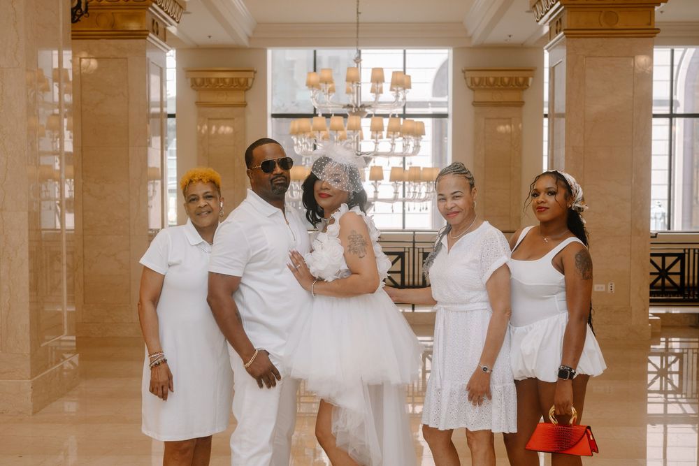 People dressed in white gather in an elegant interior space with columns and ornate architectural details.