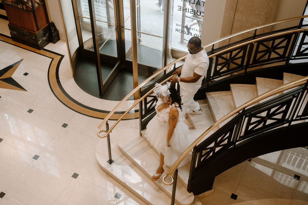 A couple performs a dramatic dip and kiss pose on a grand staircase with ornate railings.