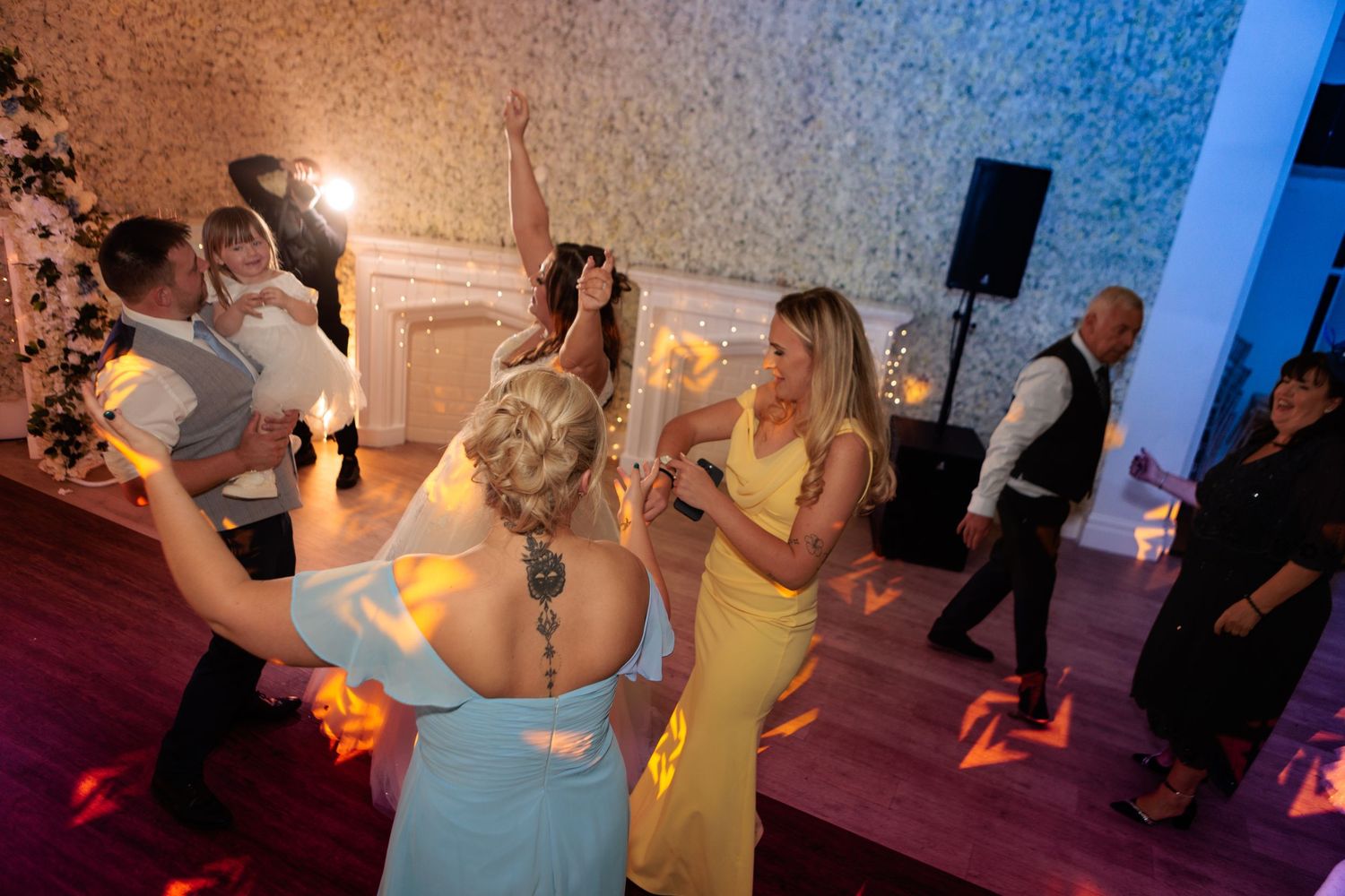 Couples dancing together on a dimly lit dance floor during a social event or celebration.