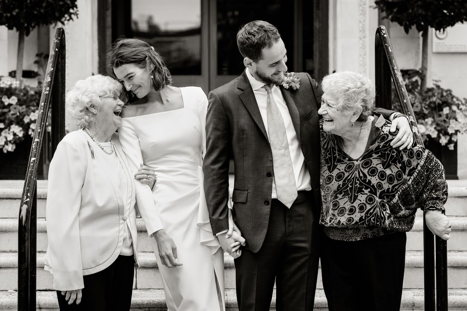 Newlyweds outside a London Town hall laugh with their grandmothers.