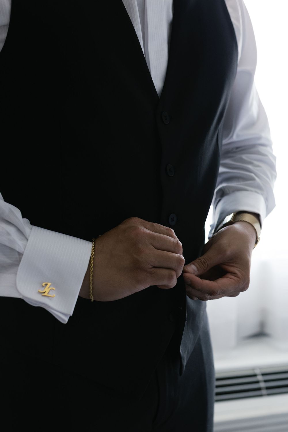 Close-up shots of someone adjusting formal attire cufflinks and buttons against a dark background.