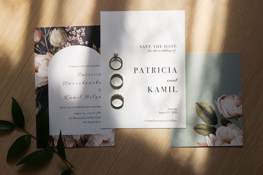 Elegant wedding invitation cards with floral designs and gold rings displayed in a row on a neutral background.