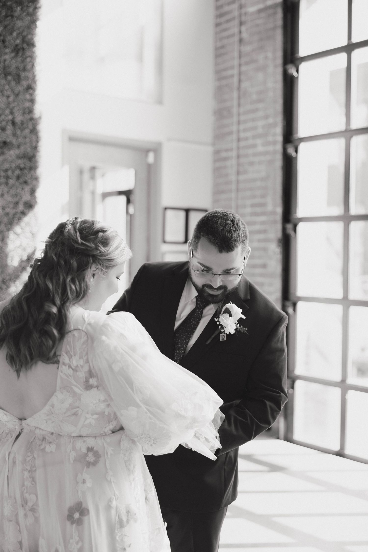 Black and white photos show a romantic dance sequence between newlyweds in an elegant venue with brick walls and windows.