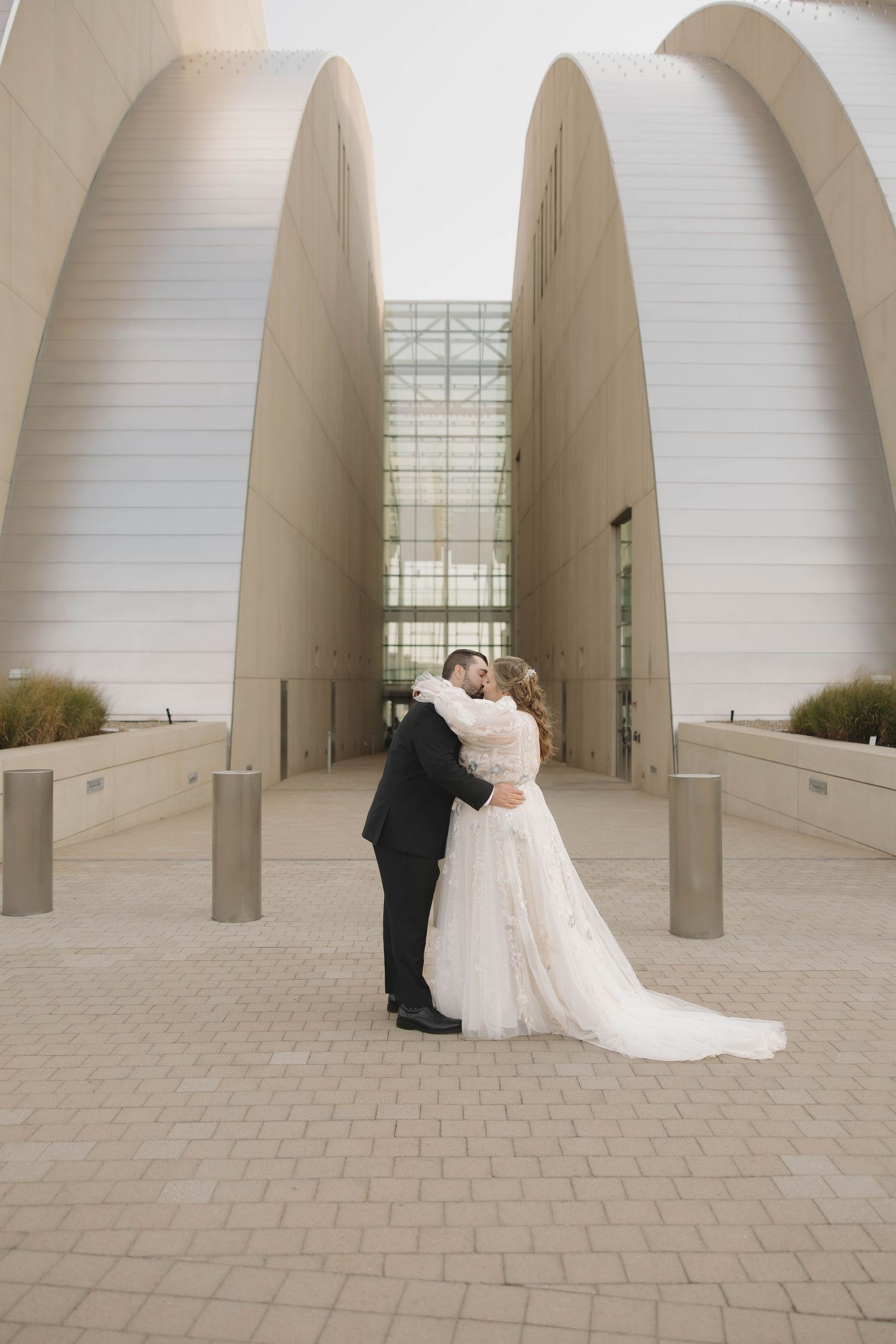 A romantic wedding photoshoot under modern white architectural arches with stone pavement.