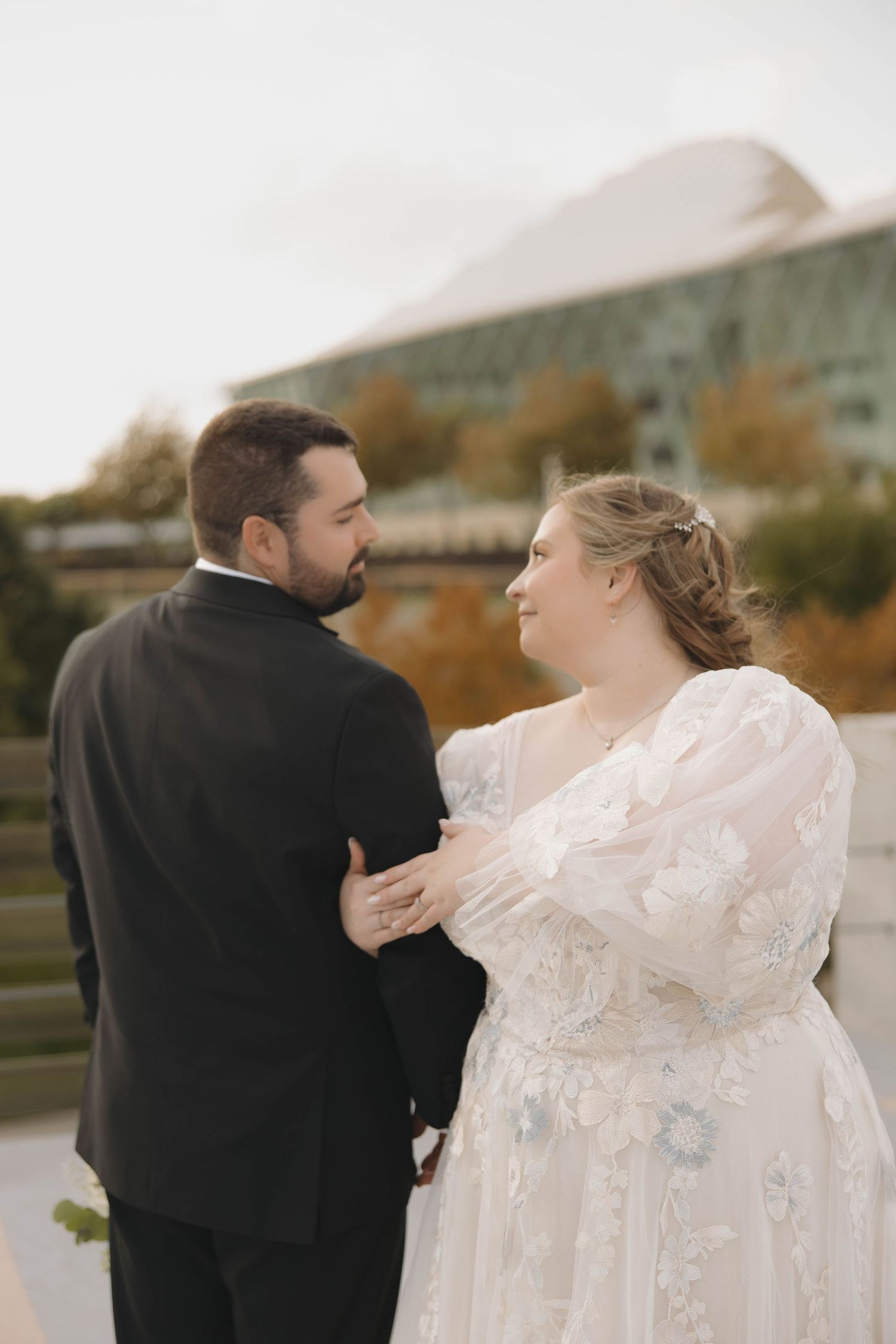 A couple shares an intimate moment in their wedding attire against an autumn backdrop.