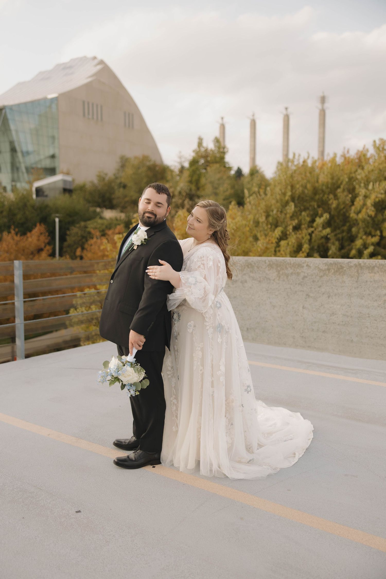 A wedding couple shares a first look moment on a rooftop walkway during their autumn outdoor photo session.