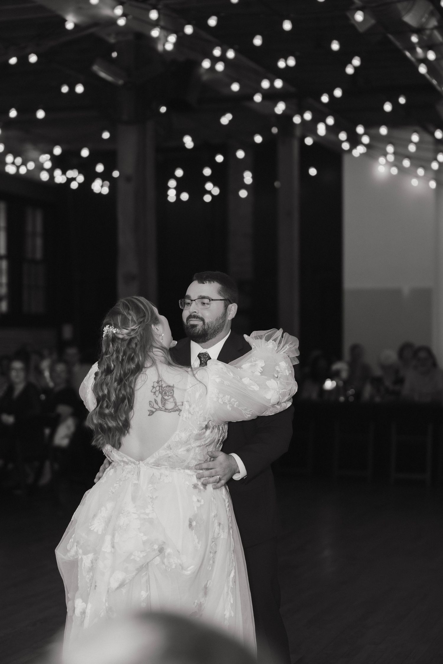 A couple shares their first dance under twinkling lights at their wedding reception.