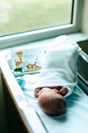 Newborn baby resting peacefully in a hospital bassinet.