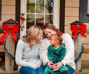 Family wearing coordinated green and white outfits sits together on outdoor porch steps during holiday season.