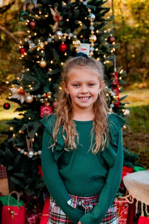 Festive holiday photos with decorated Christmas tree and someone wearing a green sweater and plaid skirt.