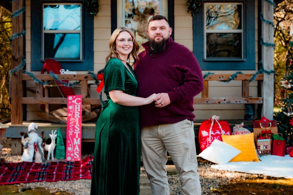A couple embraces while dancing on a rustic wooden porch decorated with autumn leaves and string lights.