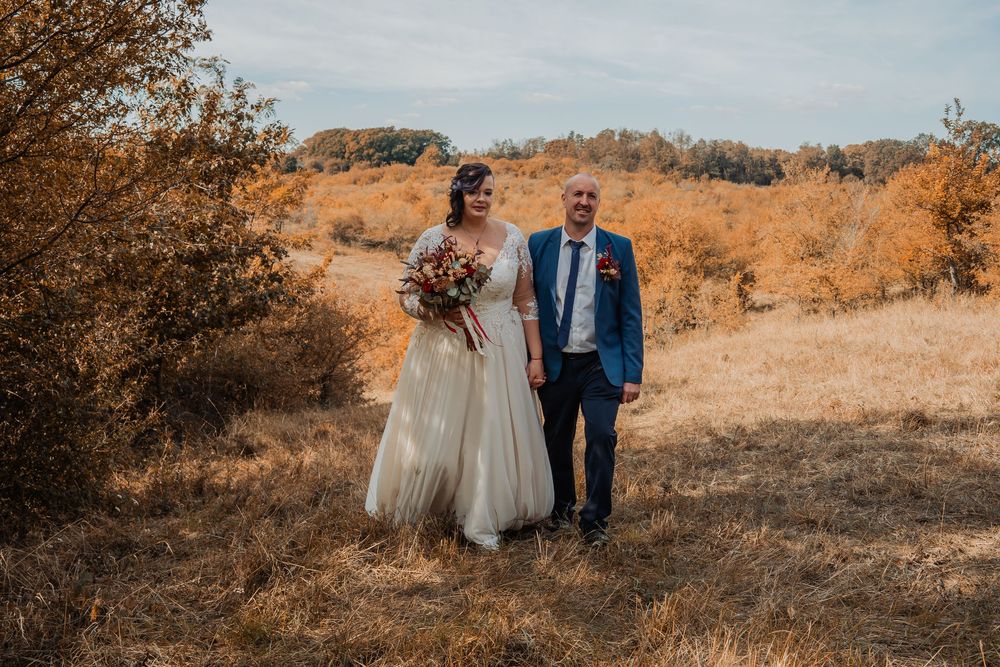 Pár sétál az őszi arany mezőn naplemente fotózás közben.