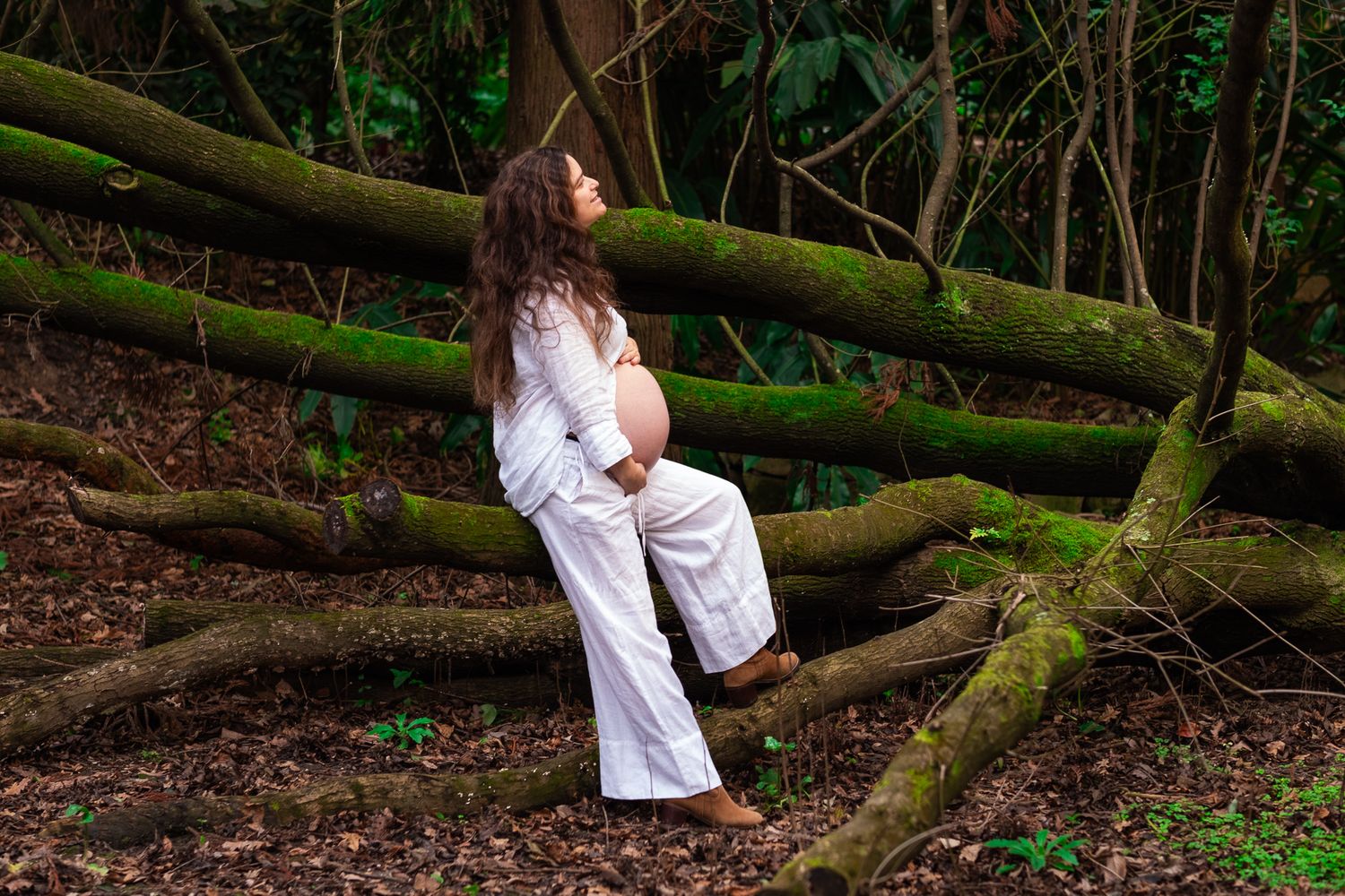 A beautiful pregnant woman in a green botanical garden, photo take by Raquel Soares Photography