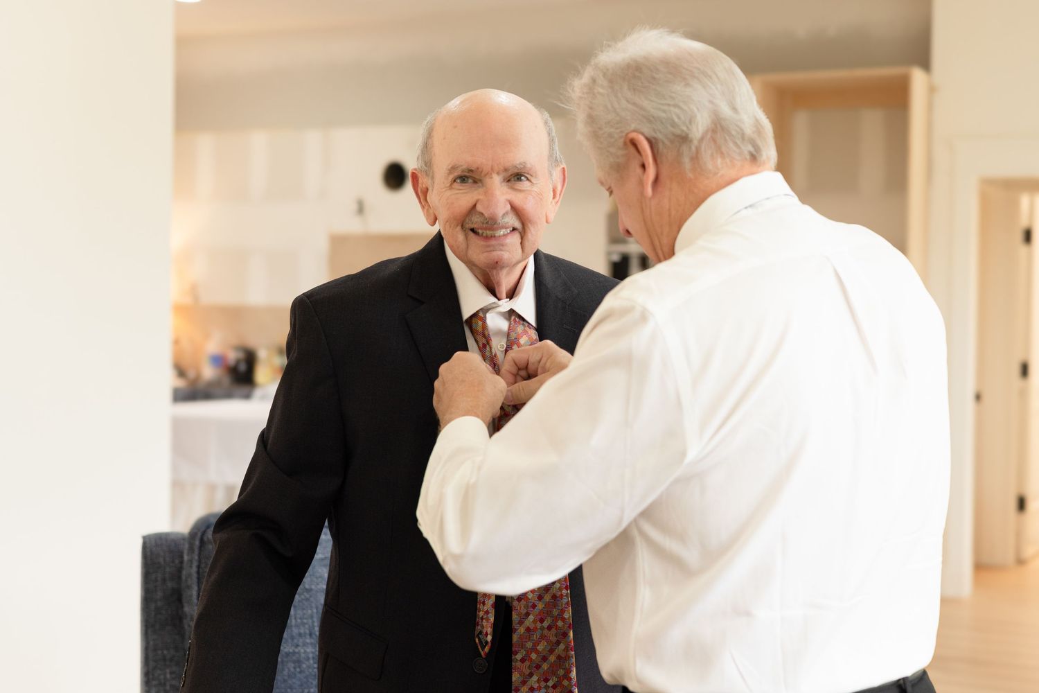Two people in professional attire share a lighthearted moment in an office hallway.