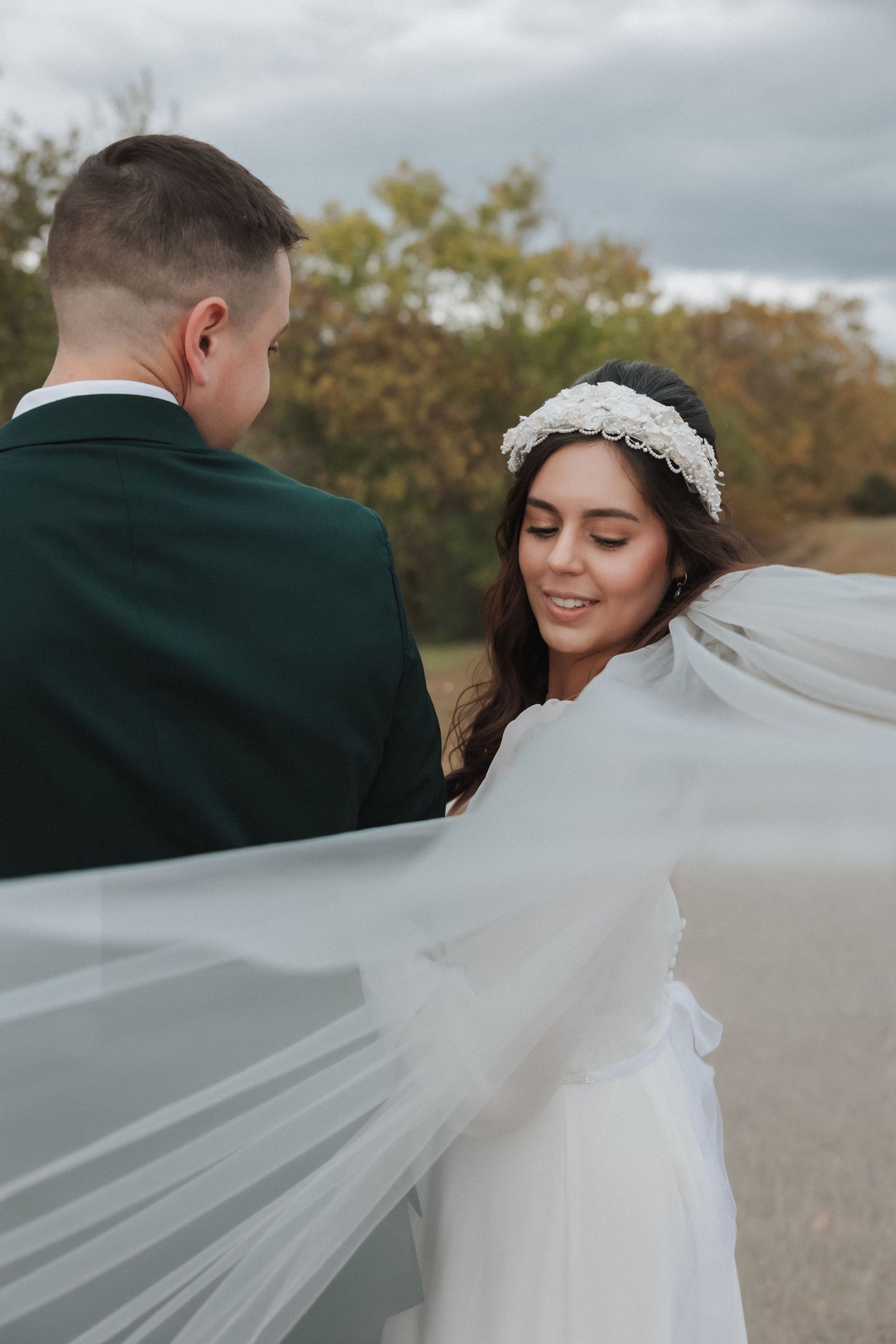 A romantic wedding photo series showing a bride's veil flowing in the wind as she stands with her groom outdoors.