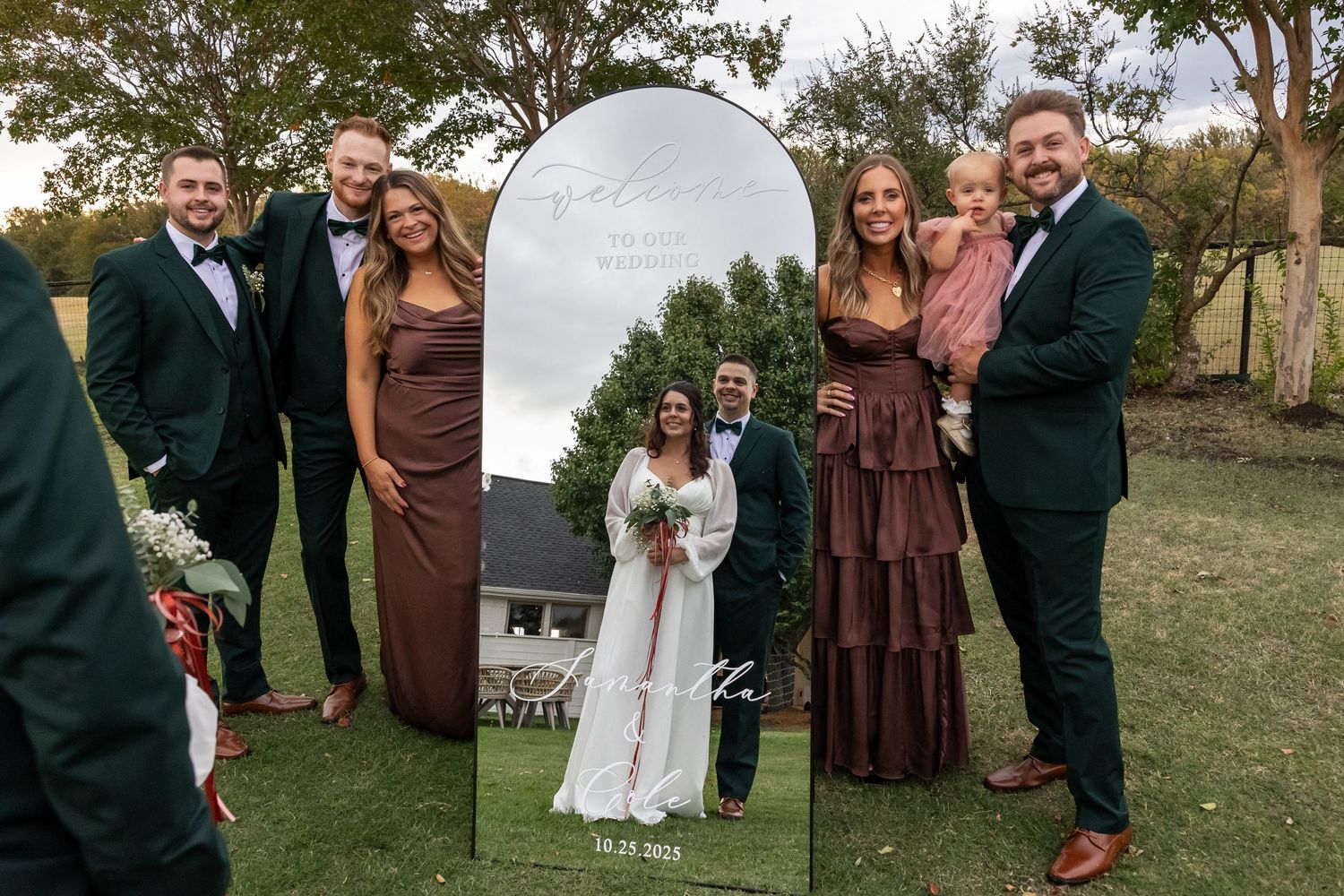 Wedding party poses together outdoors on a grassy hill during autumn celebrations.