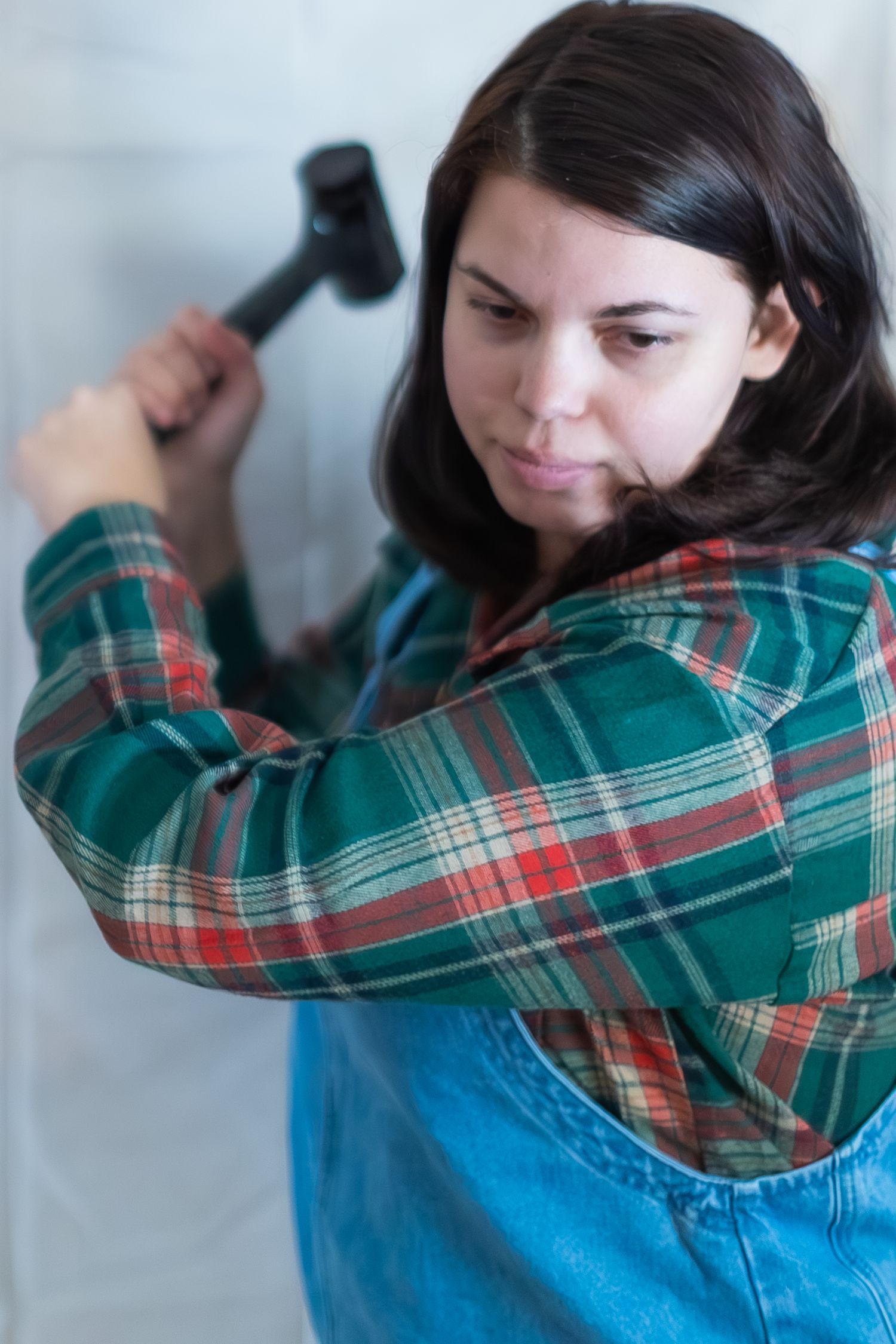 A person wearing a plaid shirt and overalls is shown in a sequence of dance-like movements against a light background.