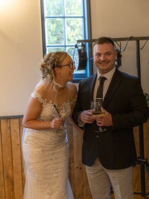 A couple shares drinks and laughter in a rustic venue with wooden wall panels.