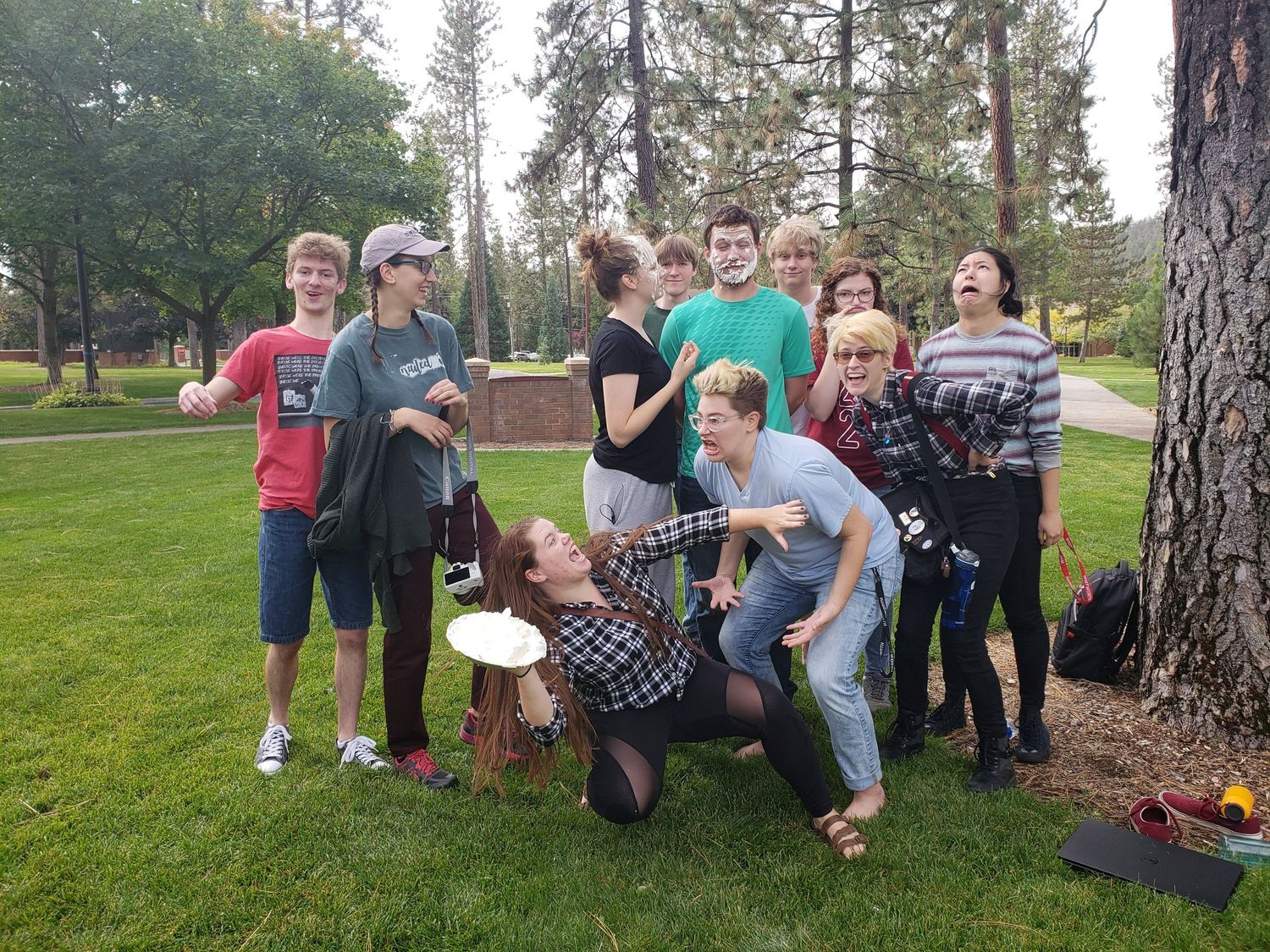 Group of college students posing playfully outdoors in a park setting during a Cool Whip improv comedy meetup.
