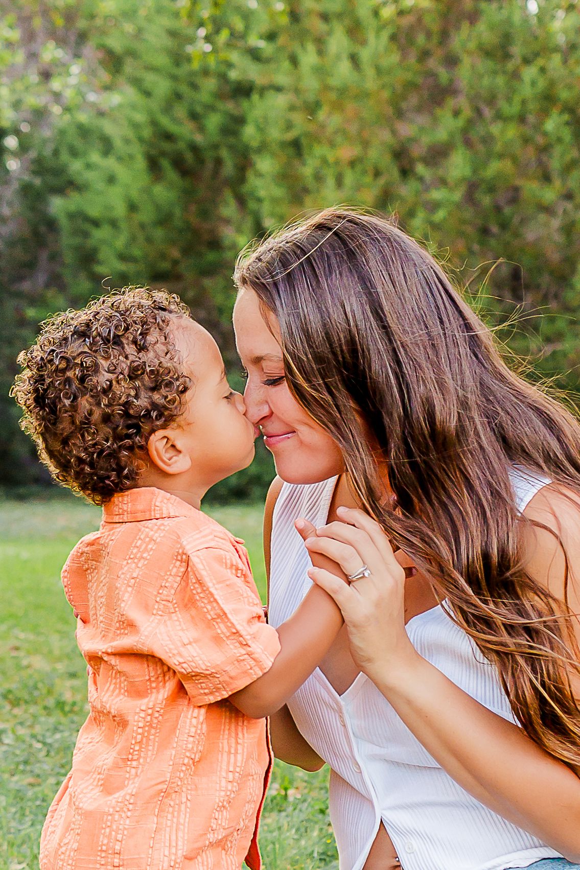 A sweet sequence of tender moments between parent and child in an outdoor setting with natural greenery.