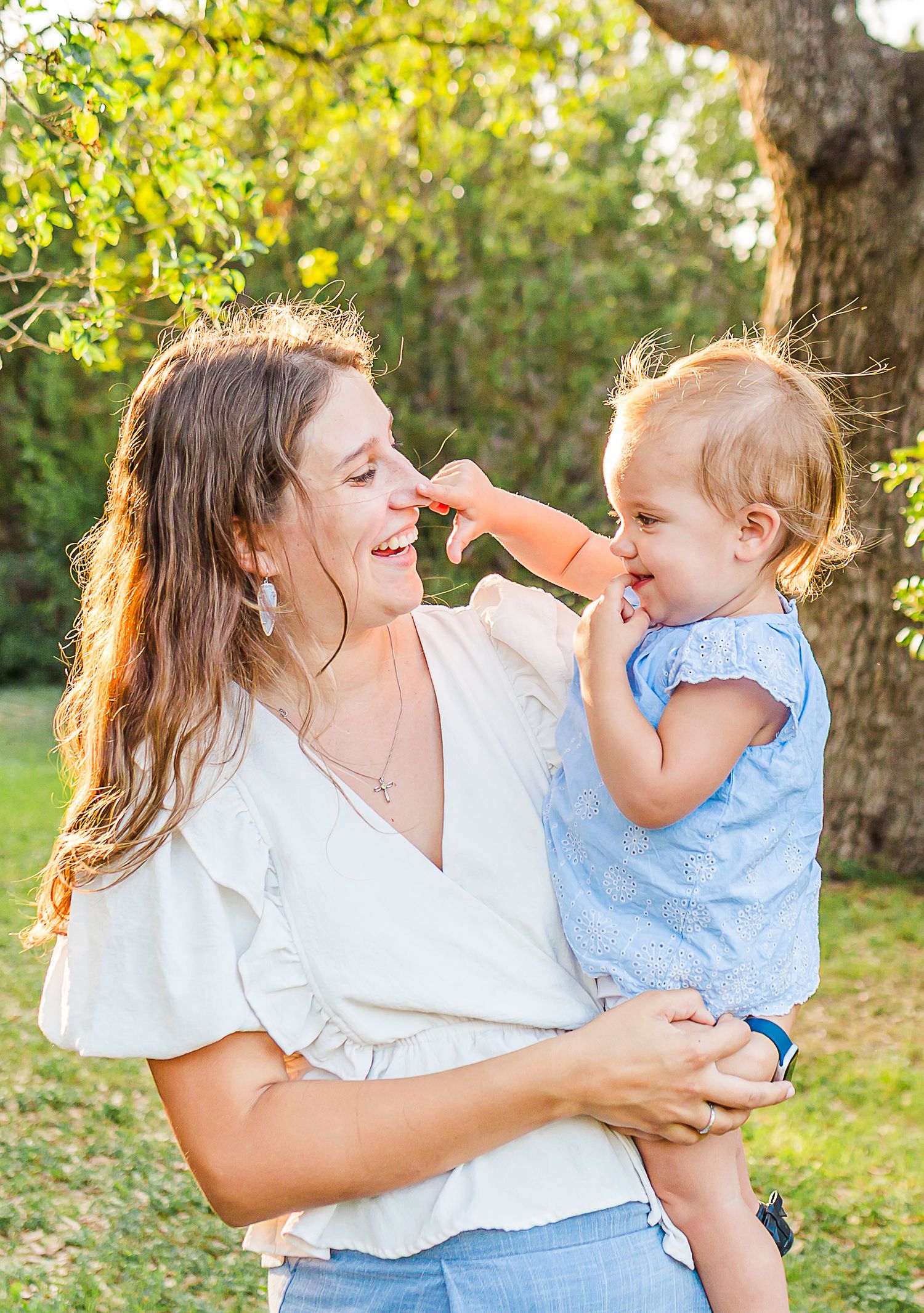 A joyful outdoor photoshoot in a sunlit garden captures candid moments of laughter and playful interaction.