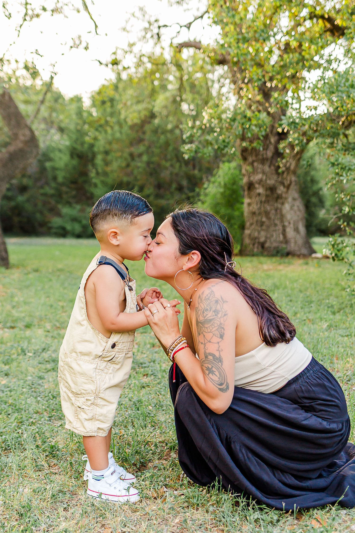 A tender outdoor moment captured in a grassy field with trees in the background.