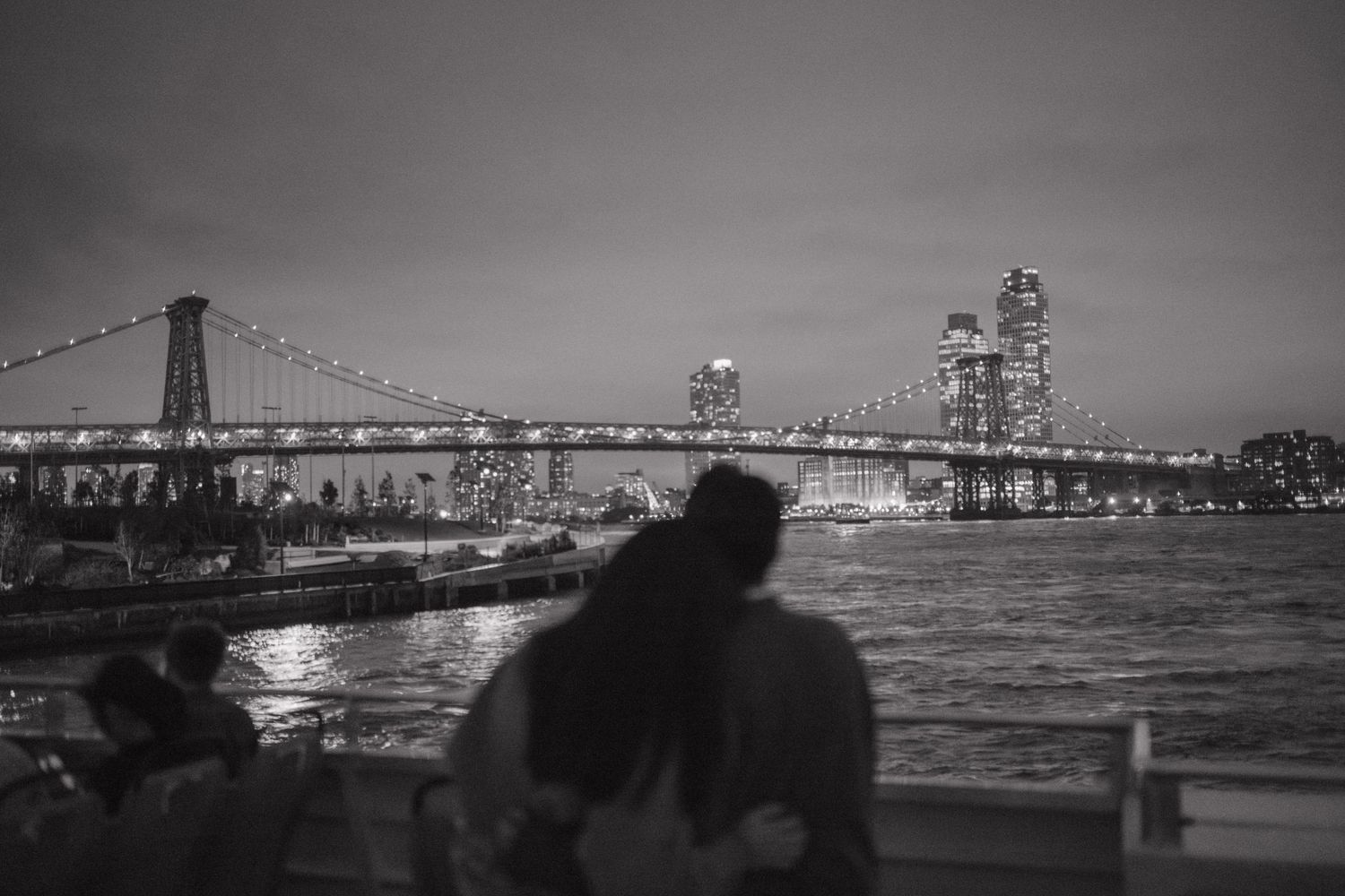 A series of black and white panoramic photographs showing the San Francisco Bay Bridge at night with city lights reflecting on water.