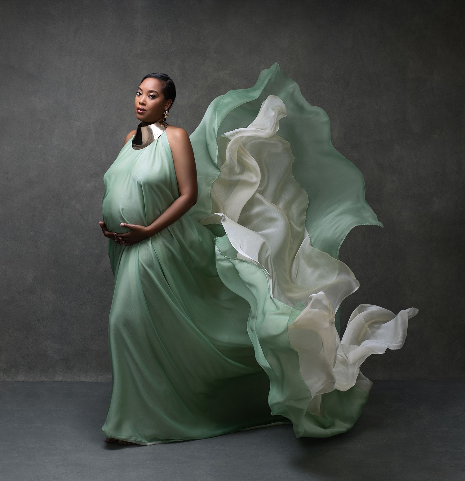 A woman wearing a flowing green dress with dramatic ruffles and billowing fabric, creating a striking visual effect.