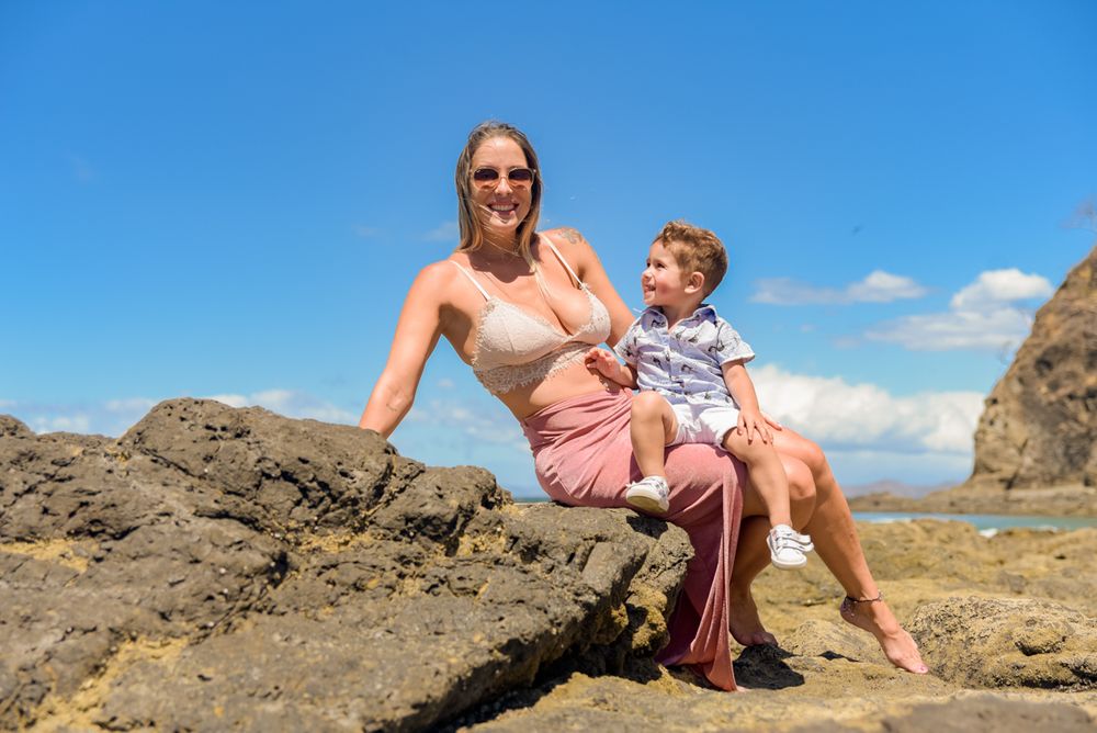 Family enjoying a sunny day exploring rocky coastal terrain with blue skies and ocean views.