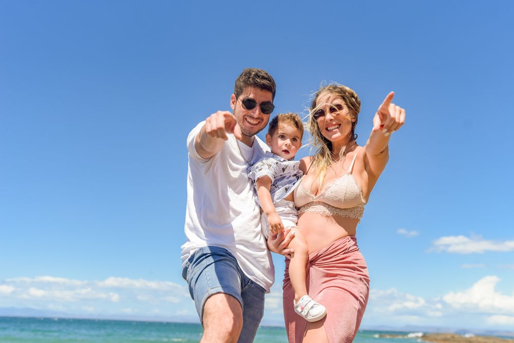 Family spending time together on scenic rocky beach overlook during bright summer day.