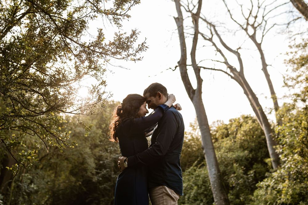 Natural engagement session in Lisbon, couple hugging and smiling in Gulbenkian Garden surrounded by greenery