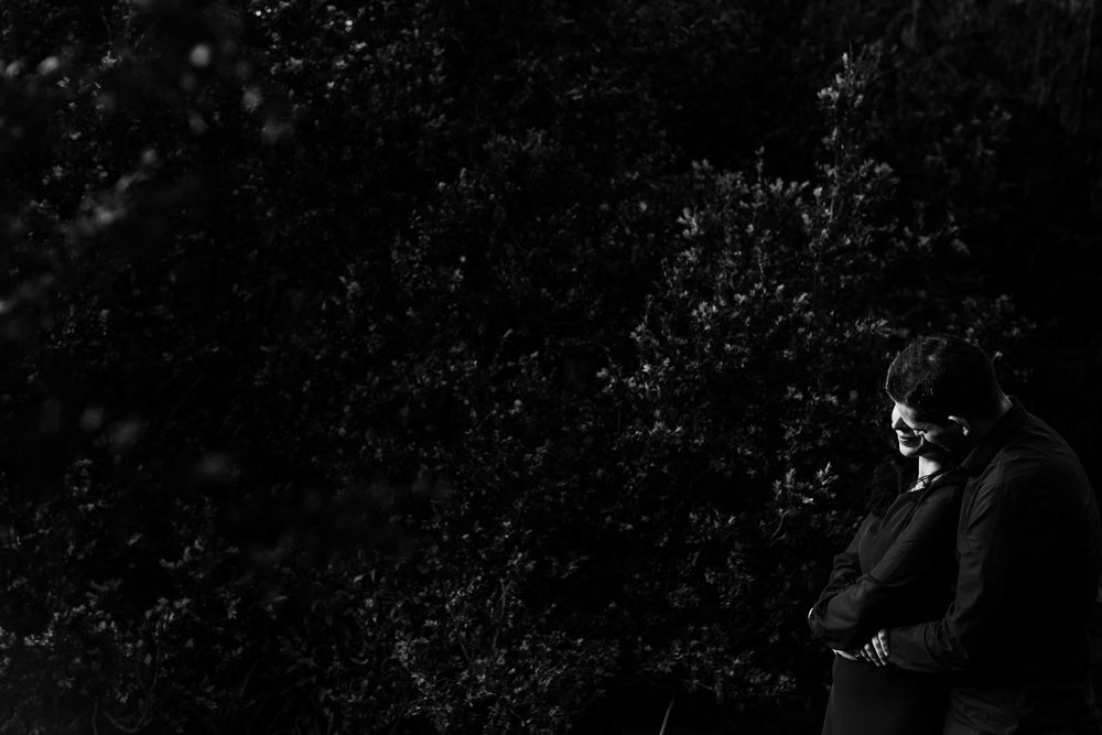 Moody black and white portrait of couple hugging during romantic photoshoot in Lisbon park