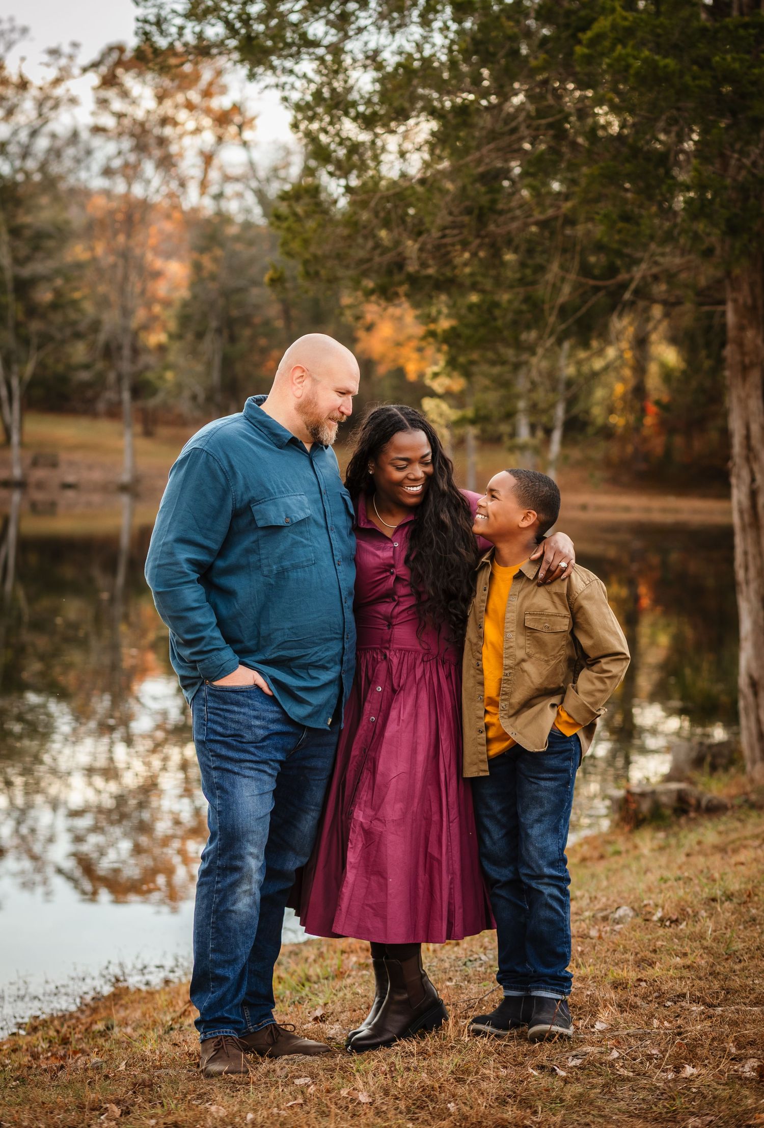 Edited image of family of three hugging against a warm fall backdrop, captured by Charlottesville baby and newborn photographer.