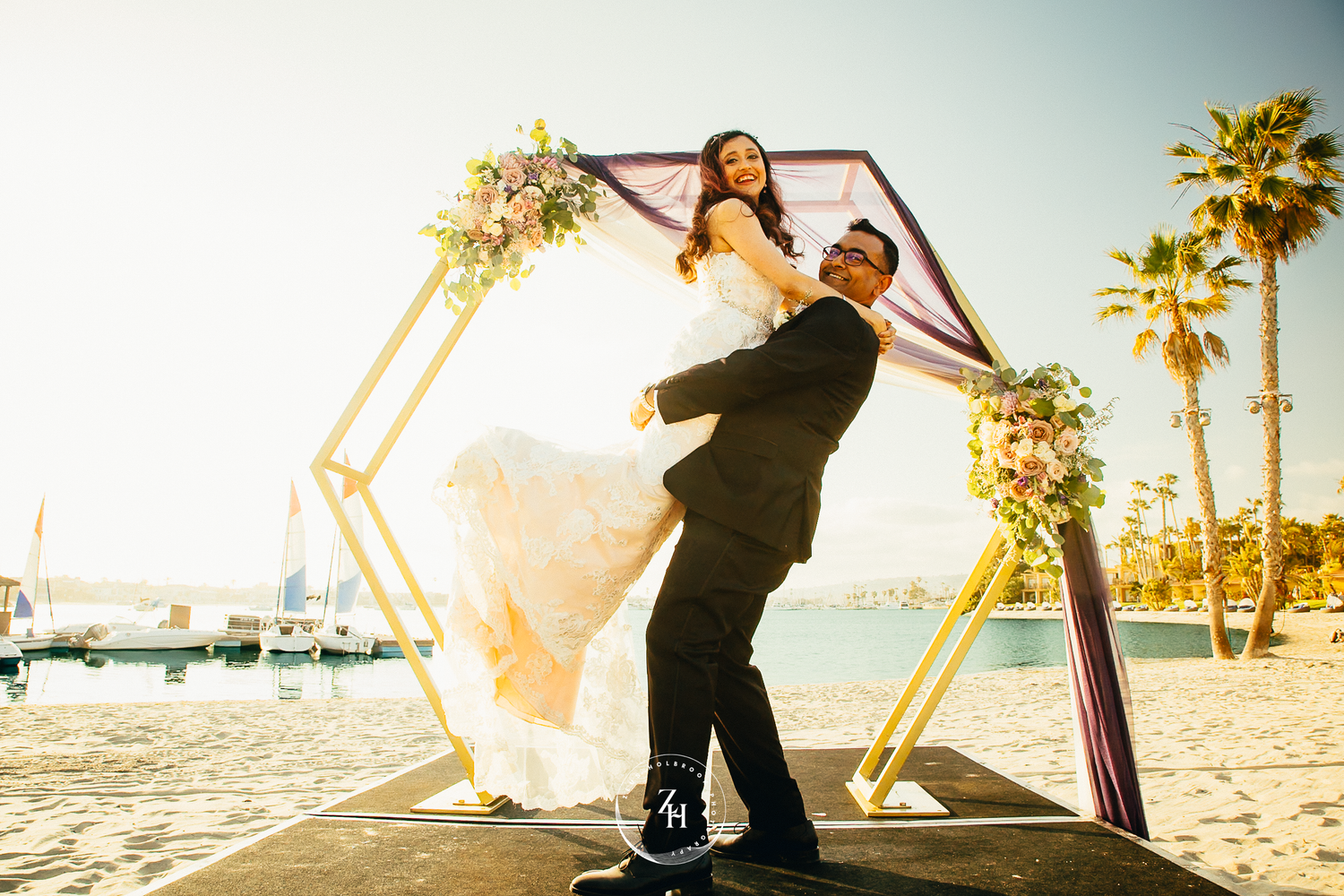 A couple jumping into each other's arms at Bahia Resort beach, San Diego. Photo By Zeus Holbrook Photography