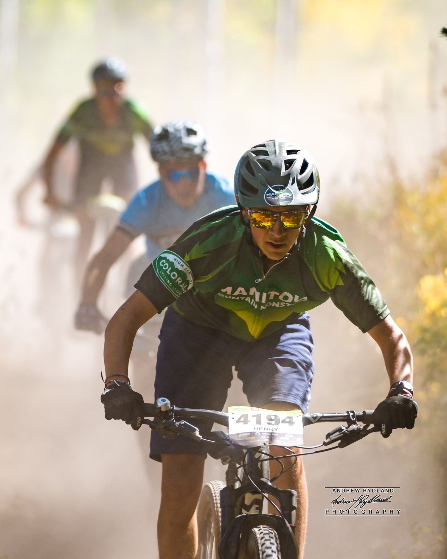 Mountain bikers racing through dusty trail conditions in summer competition.
