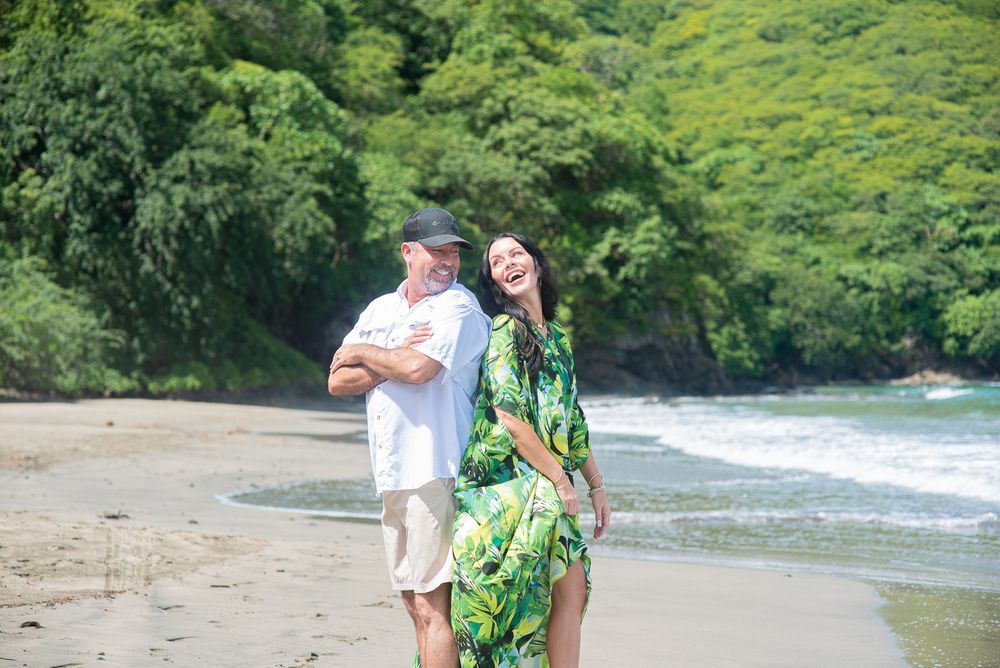 People walking along a scenic beach path surrounded by lush tropical vegetation and ocean waves in Hawaii.