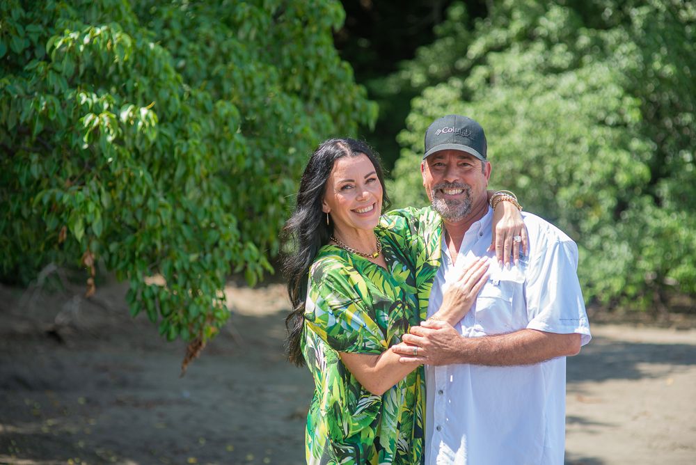 A couple shares a joyful moment while dancing together outdoors in a lush green garden setting.