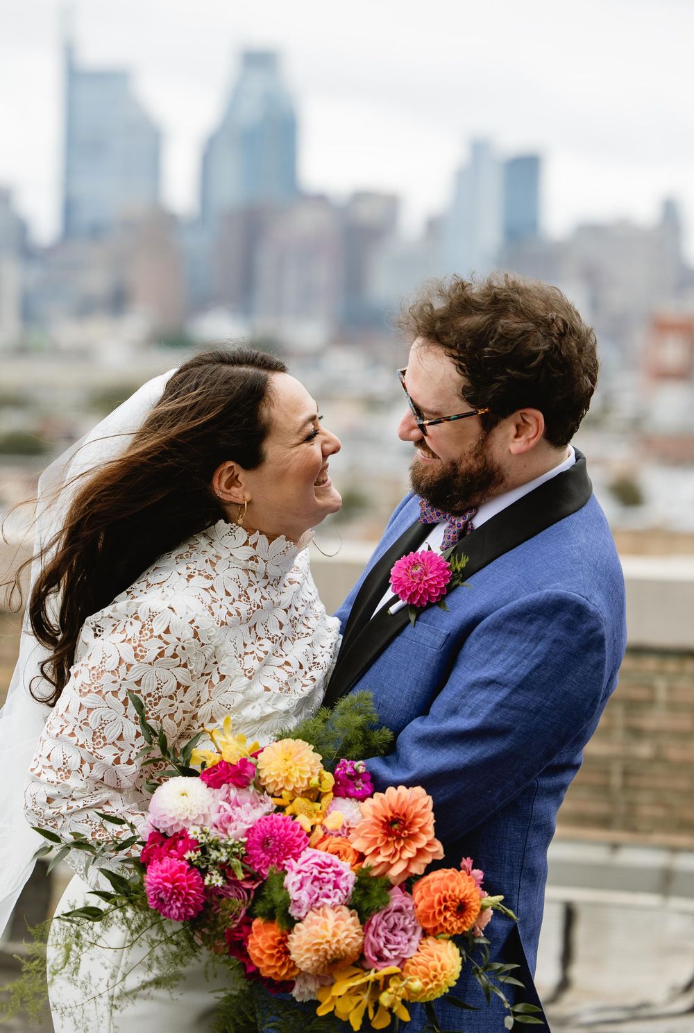 Couple shares candid moments during rooftop wedding photoshoot with colorful autumn bouquet. Bok Building Philadelphia
