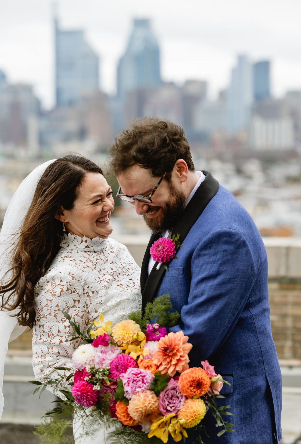 A tender wedding moment with bright floral bouquet featuring dahlias and roses against an urban backdrop.  Bok Building Philadelphia