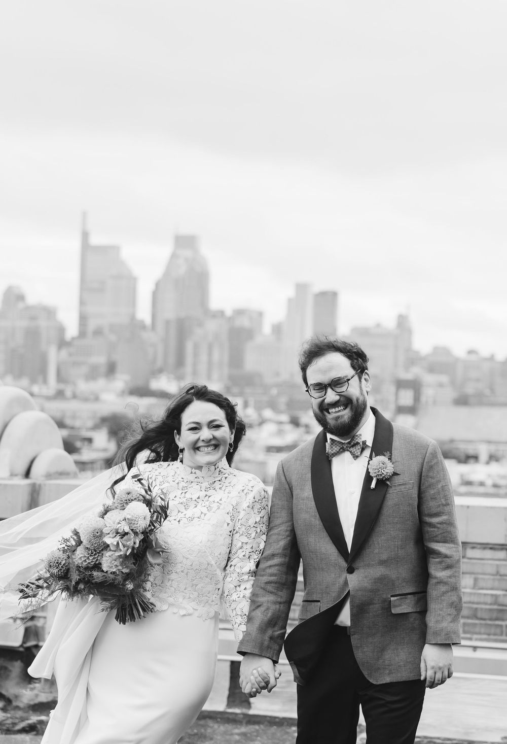 Black and white wedding photos showing candid laughter and joy on a city rooftop. Bok Building Philadelphia