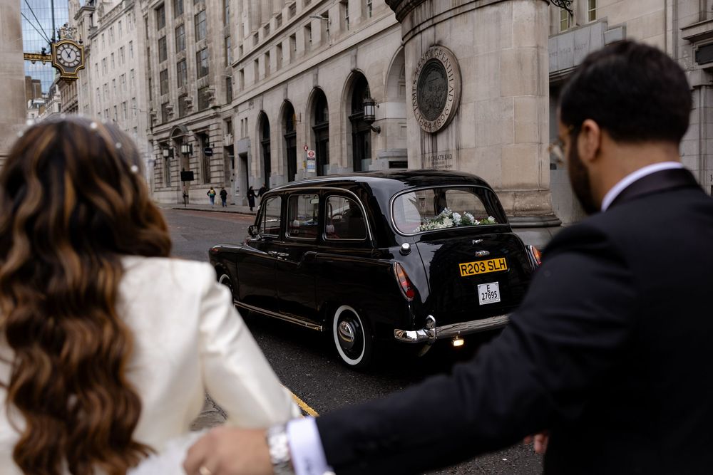 Classic black taxis parked in a row beside ornate stone buildings in London's city center.