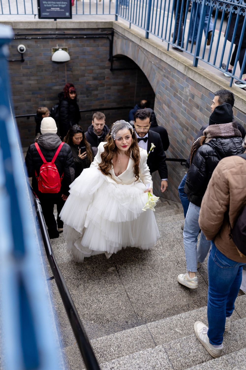 Group descending stone steps in a building with white railings and brick walls.