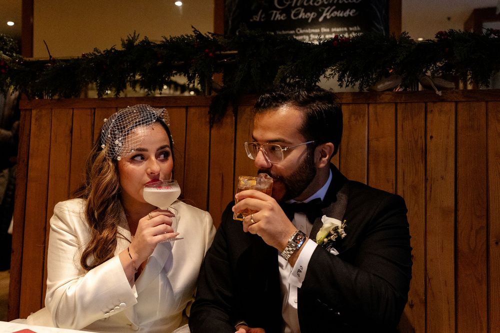 A cozy indoor wedding reception moment with two people enjoying warm drinks together.