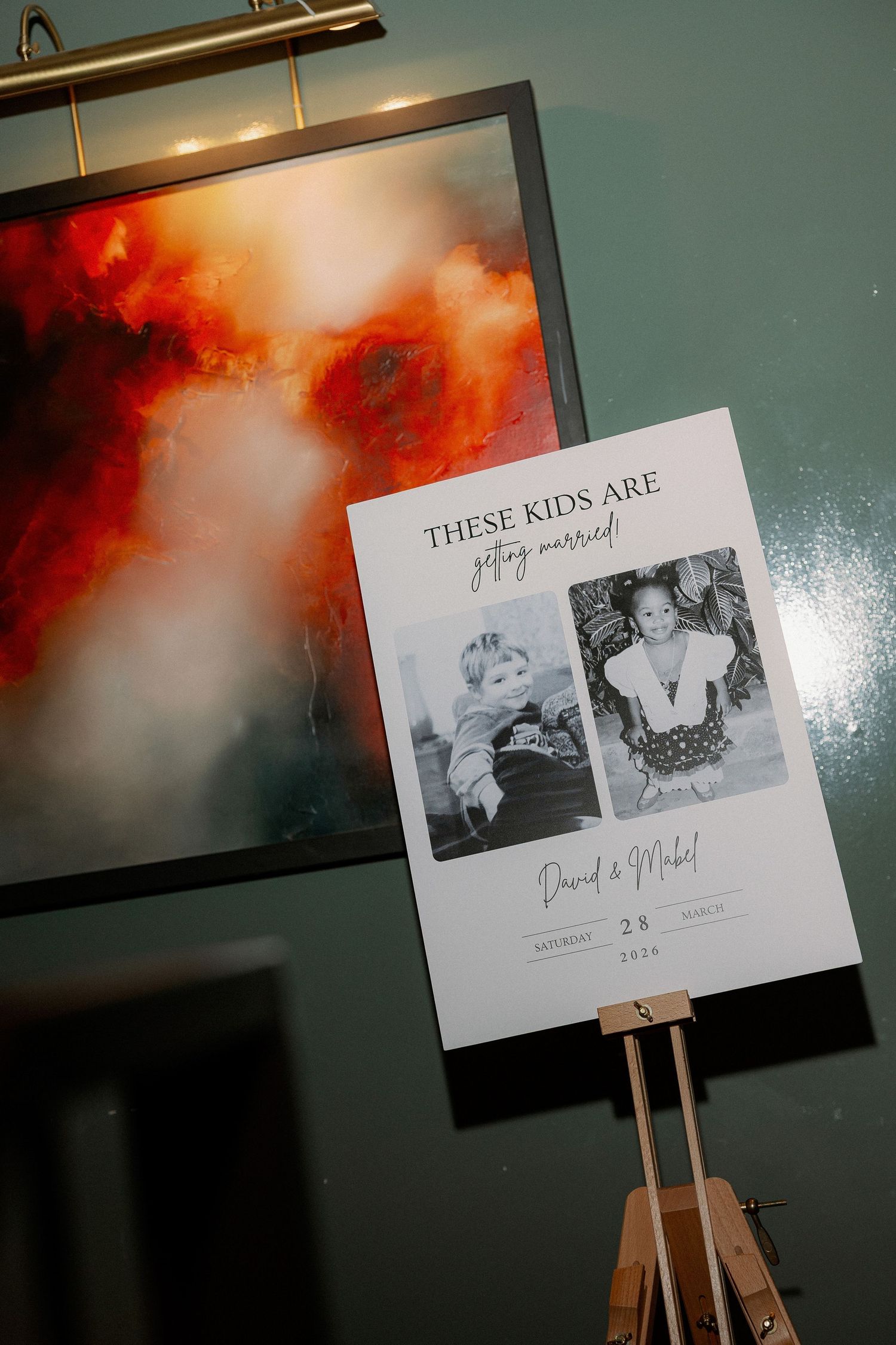A series of black and white photographs displayed on wooden easels against a dramatic orange and teal background.