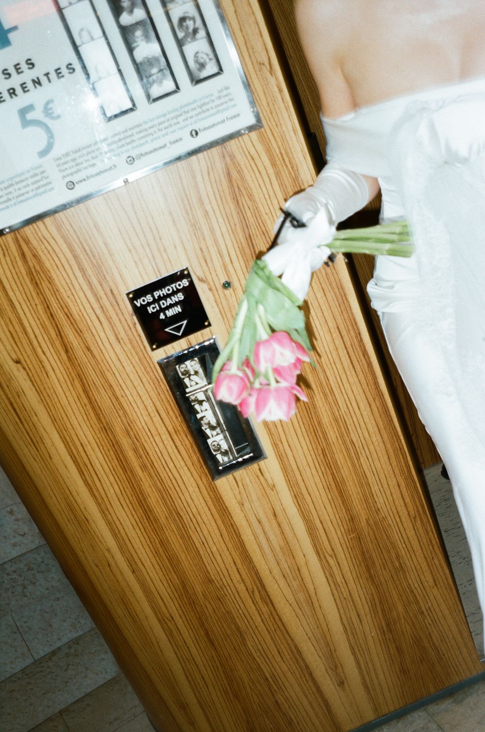 Pink tulips lay on a wooden table next to scattered papers and a black business card.