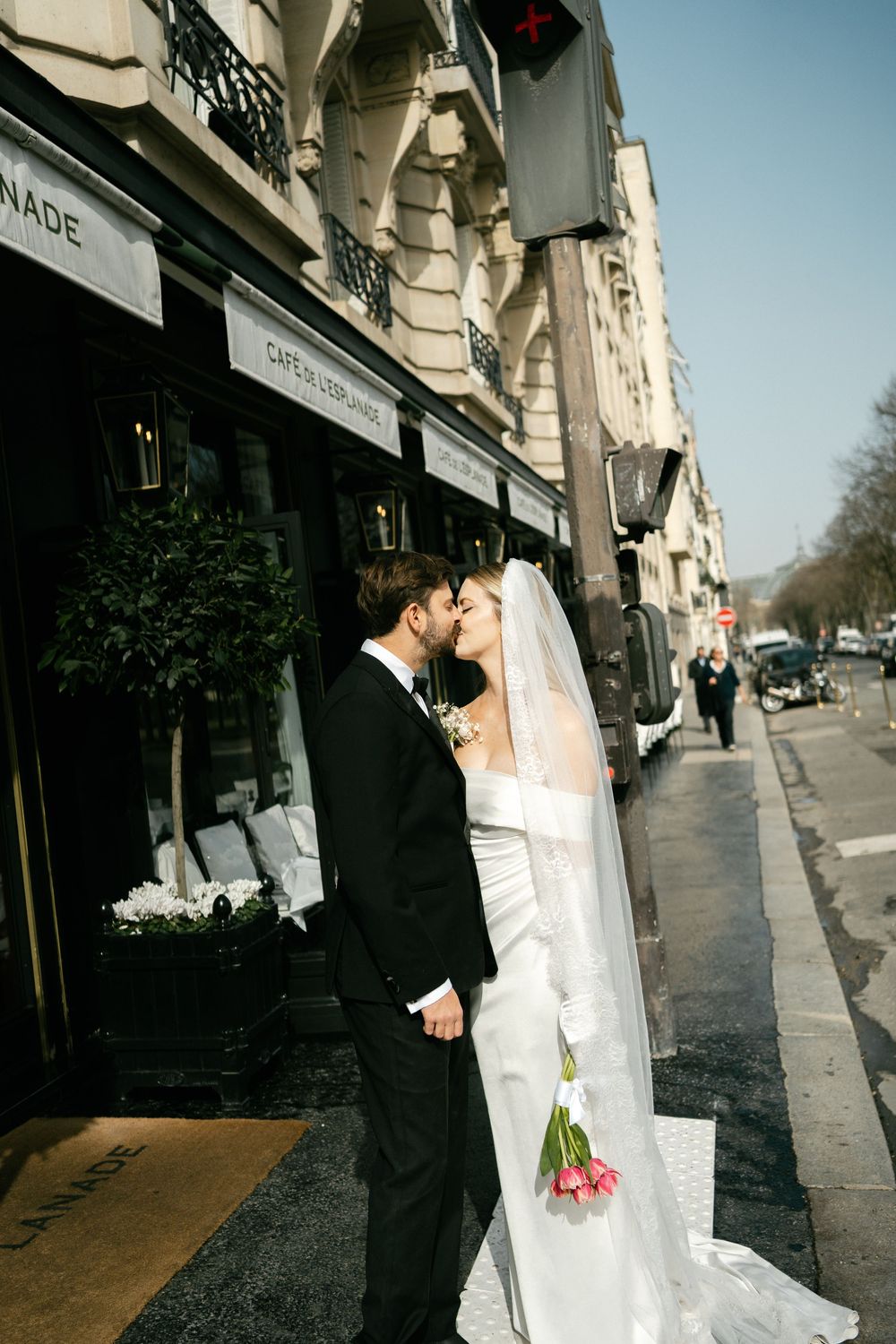 A series of four romantic wedding photos showing a couple walking together along a city sidewalk near storefronts.