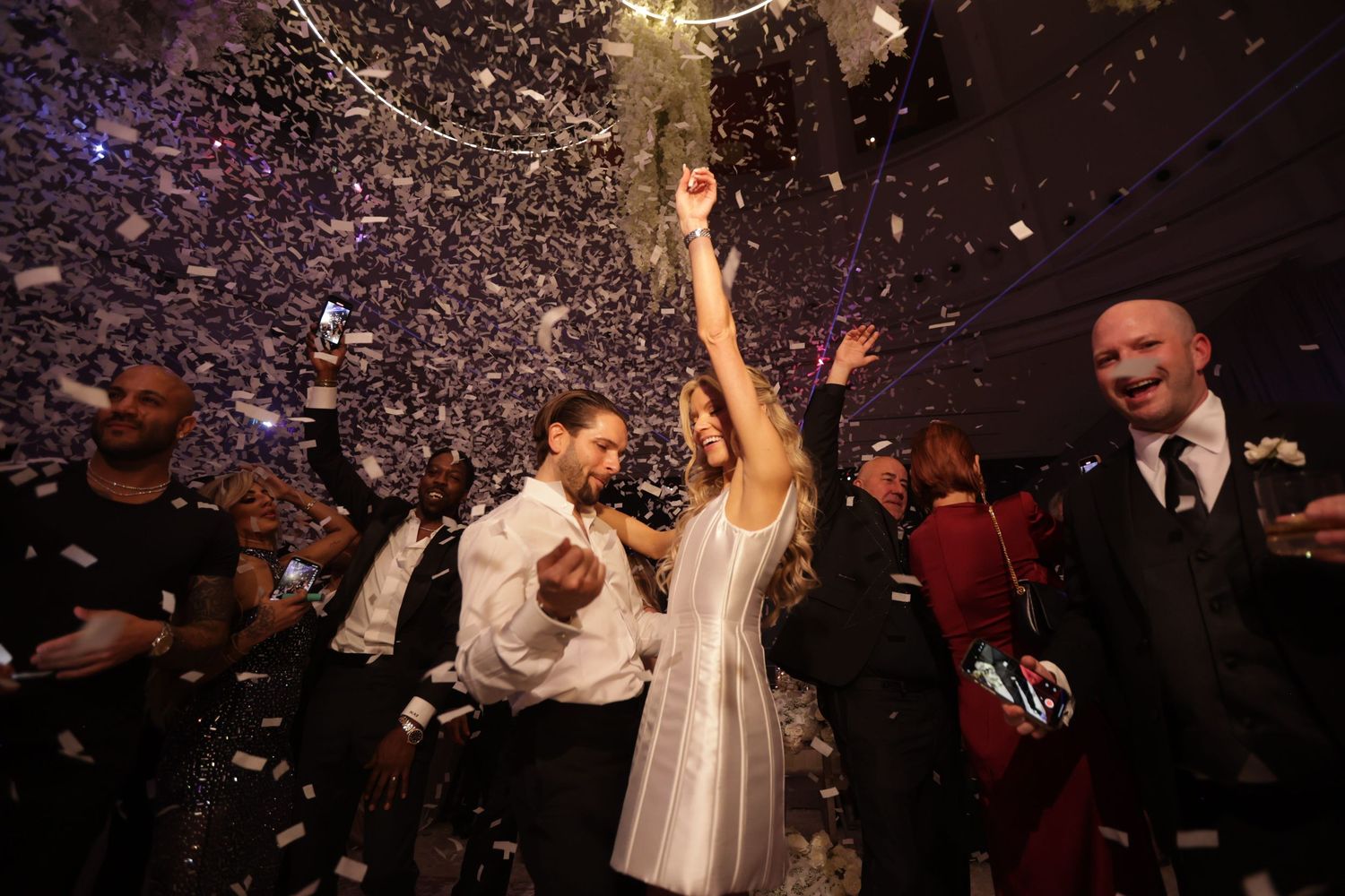 A wedding in Miami with the bride and groom dancing at their reception with confetti falling down on them and their guests.