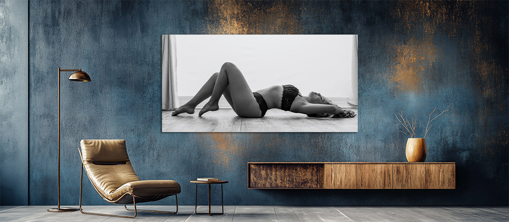 Black and white fine art print of a woman in lingerie posing gracefully displayed on a blue wall.