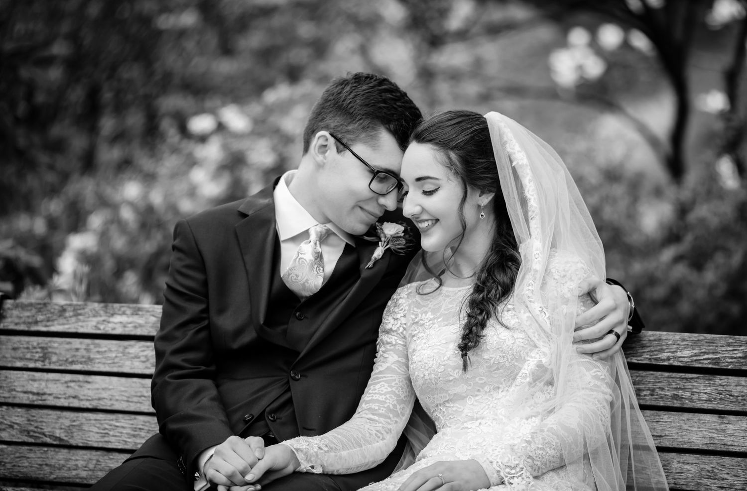 A wedding ceremony takes place in a beautiful church with gothic windows and a chandelier overhead.