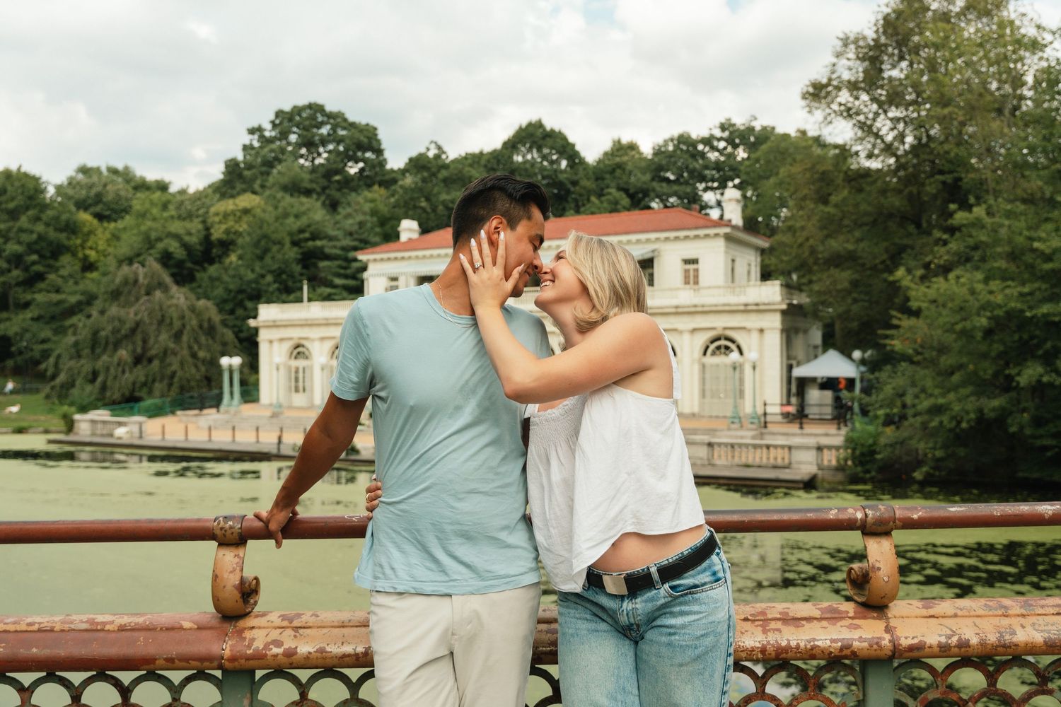 Romantic moment captured in front of historic white mansion with beautiful gardens.